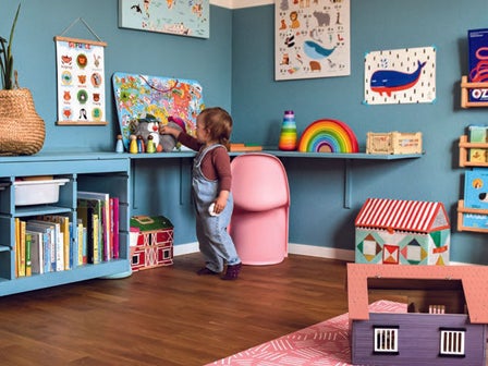 Ein Kind stellt ein Spielzeug in einem aufgeräumten Kinderzimmer in ein Regal
