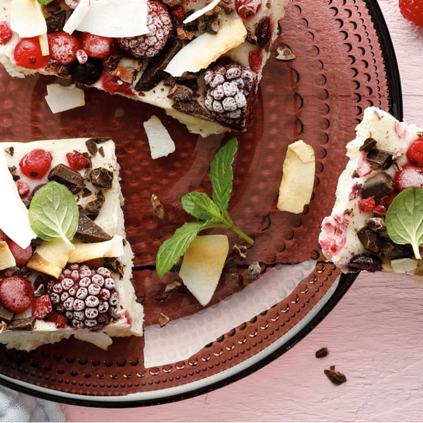 Beerige Froyo-Bites mit Beeren, Kokoschips, Schokoladenstückchen und Minze auf einem Teller.