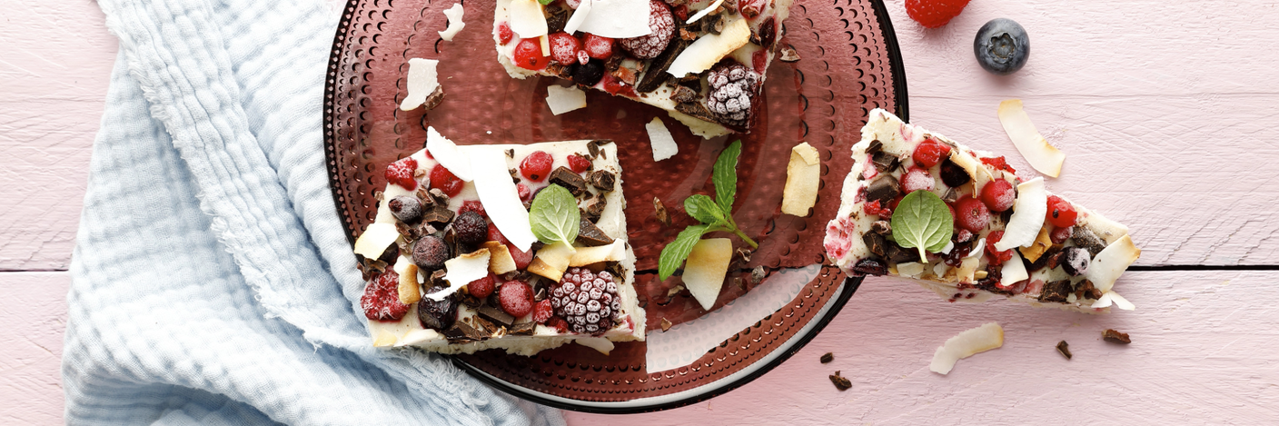 Beerige Froyo-Bites mit Beeren, Kokoschips, Schokoladenstückchen und Minze auf einem Teller.