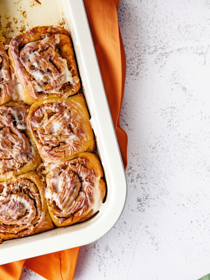 Eine Auflaufform mit Zimtschnecken auf einem orangenen Tuch