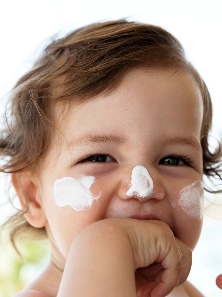 Ein Kind mit Sonnencreme im Gesicht