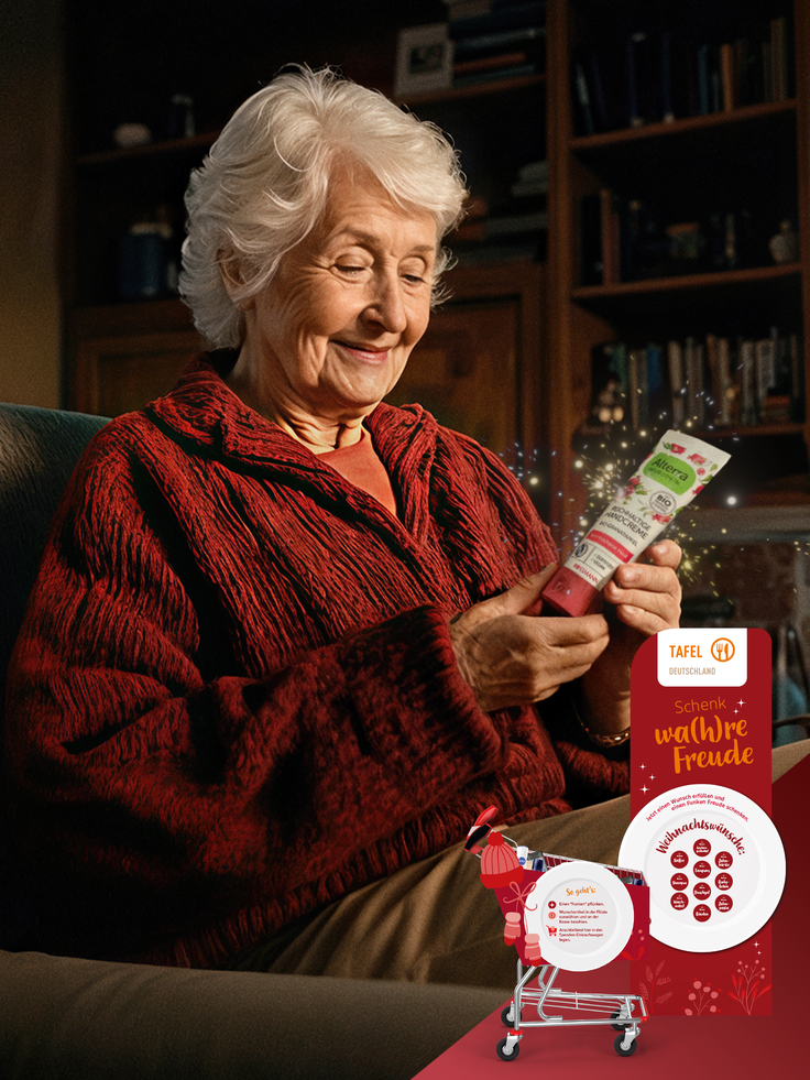 Eine ältere Frau sitzt auf dem Sofa und hat eine Handcreme in der Hand.