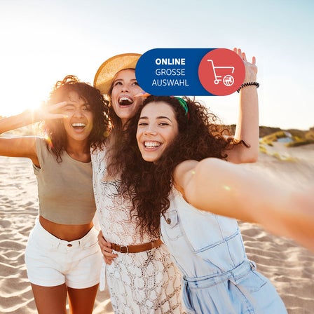 Drei Frauen am Strand, die lachen.