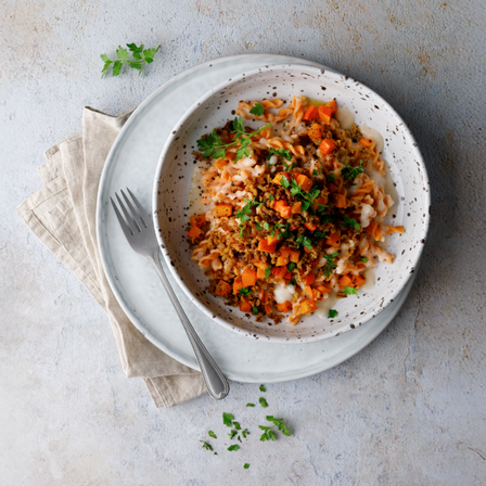 Protein Linsen-Spirelli mit Bohnensauce, Gemüsewürfeln und Kräutern in einer Schale auf hellem Teller angerichtet.