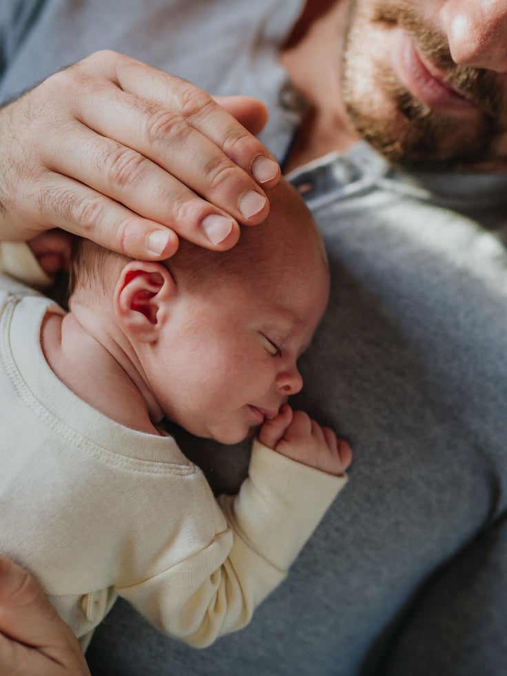 Ein Papa kuschelt mit seinem Baby.