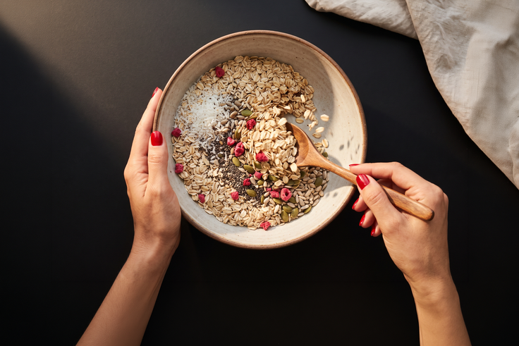 Haferflocken, Kokosraspeln, Chiasamen, Kürbis- und Sonnenblumenkerne werden mit Himbeeren für fruchtige Kokos-Müsliriegel mit Chia-Crunch vermischt.