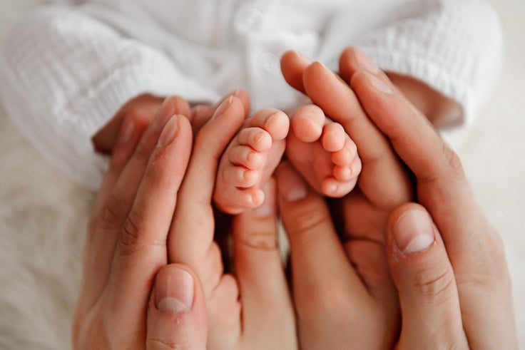 Baby's feet in in the hands of parents. Closeup photo. Happy Family concept. 