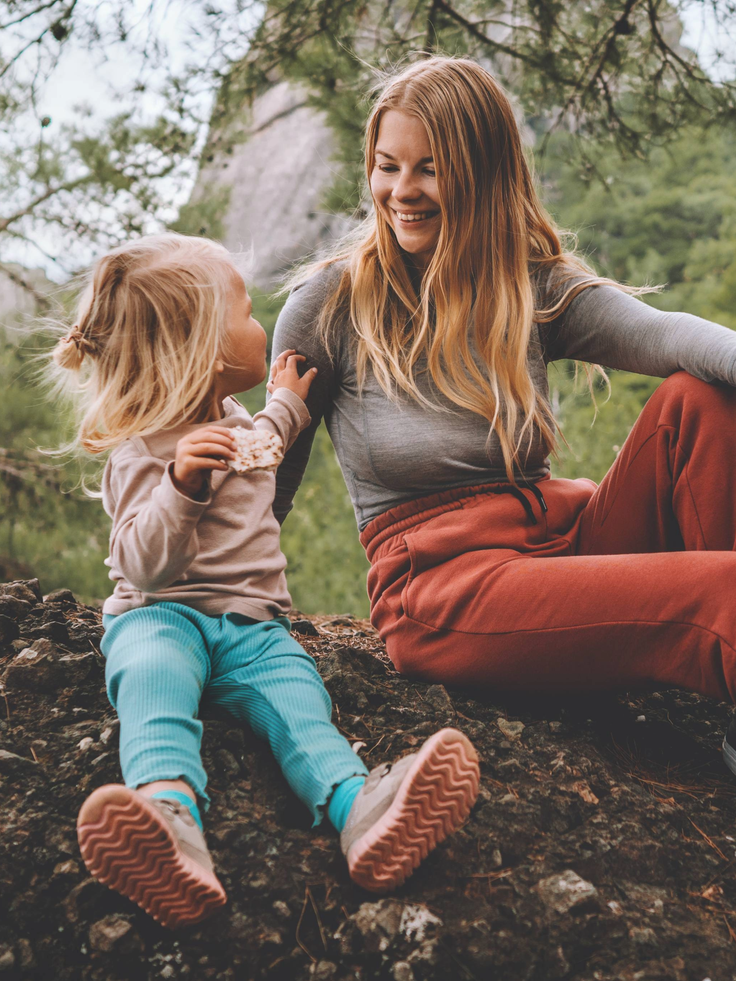 Eine Frau und ein Kind sind im Wald und essen einen Snack.