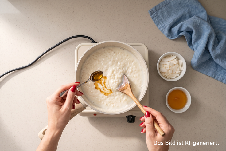 Reis wird in einem Topf auf einer Kochplatte gekocht. und mit Agavendicksaft und Kokosraspeln verfeinert.