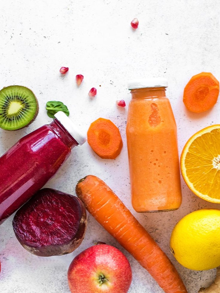 Von oben fotografierte Saftflaschen und Gemüse-und Obstsorten