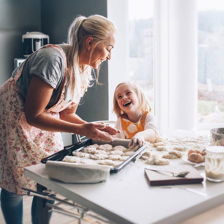Eine Frau backt mit einem Kind in der Küche.