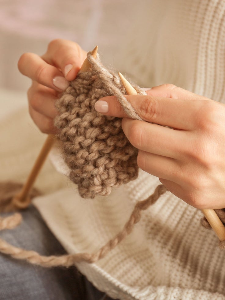 Zwei Hände, die etwas stricken