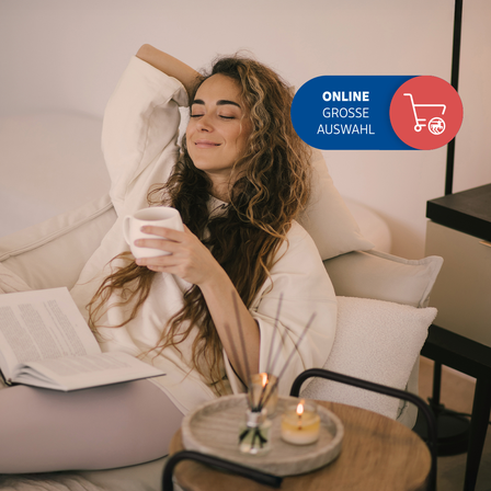 Eine Frau liegt auf dem Sofa und liest ein Buch. 