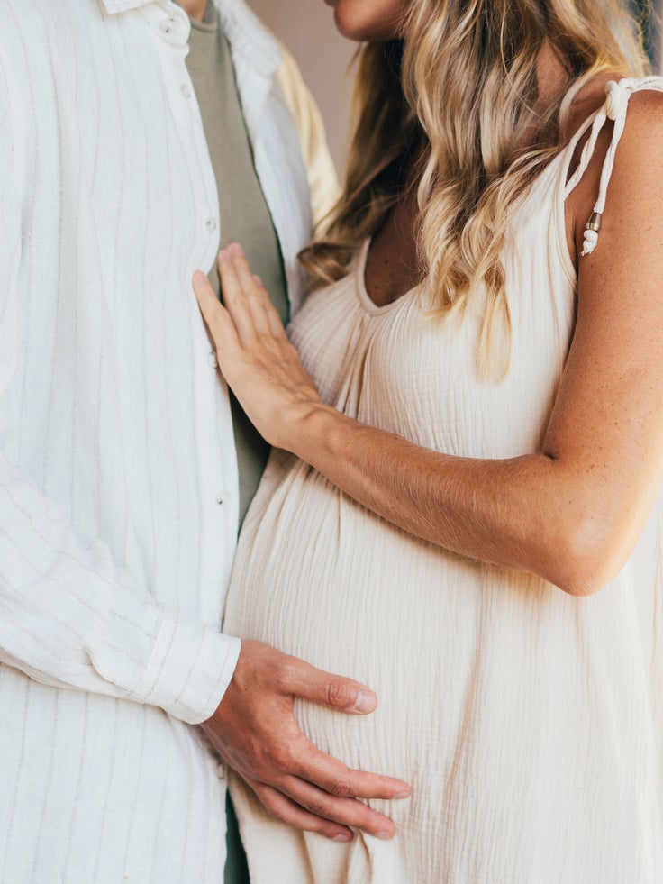 Abgebildet ist eine schwangere Frau und ein Mann, die sich umarmen