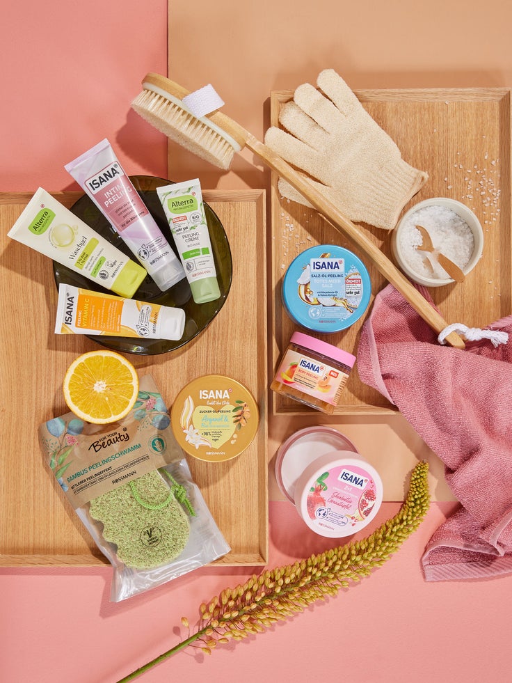 Verschiedene ISANA Körperpflegeprodukte auf einem Holzbrett mit rosa Hintergrund