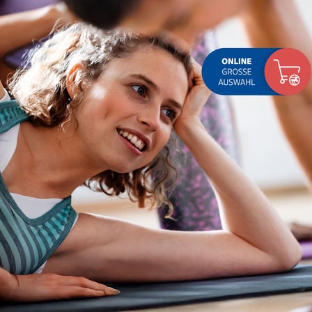 Ein Frau liegt auf einer Yogamatte.