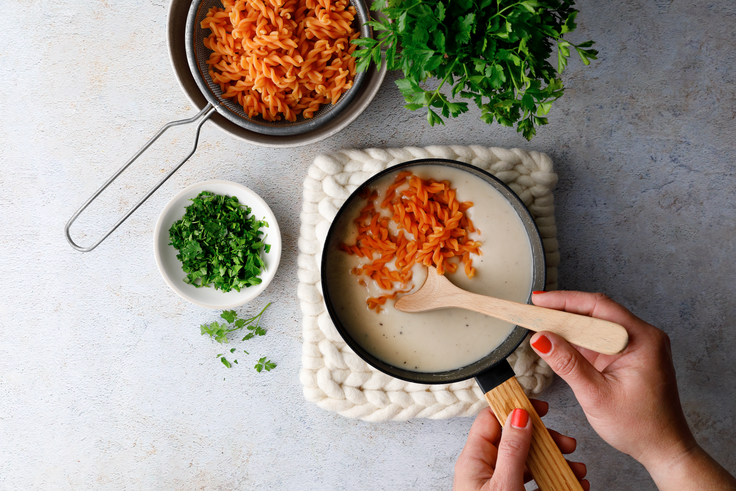 Linsen-Spirelli werden mit cremiger Bohnensauce vermischt und zum Servieren mit Petersilie vorbereitet.