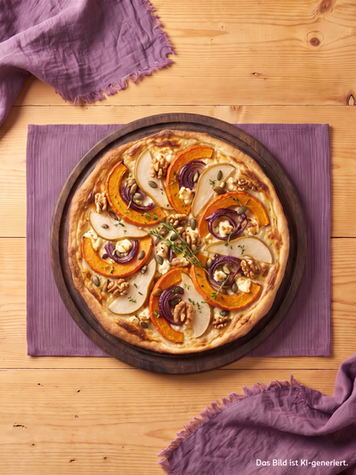 Herbstflammkuchen mit Kürbisscheiben, Birnenspalten, roten Zwiebeln und Walnüssen auf rustikalem Holzbrett serviert.