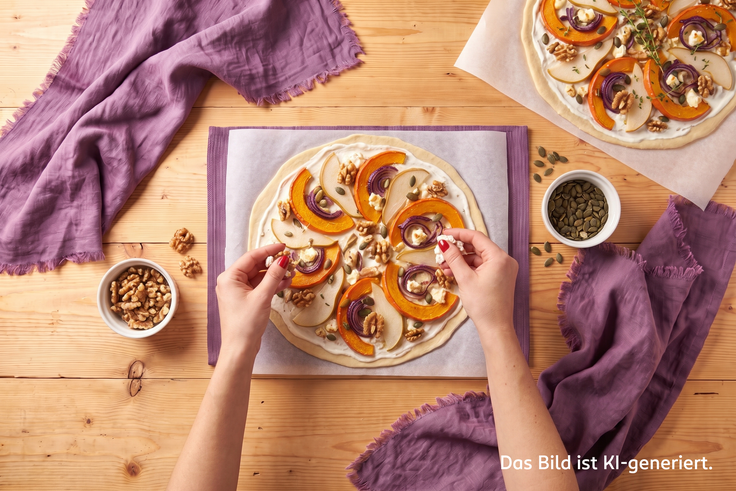 Schritt 4 des Flammkuchen-Rezepts: Ziegenkäse wird auf den mit Kürbis, Birne und roten Zwiebeln belegten Teig gebröckelt, bereit zum Backen.