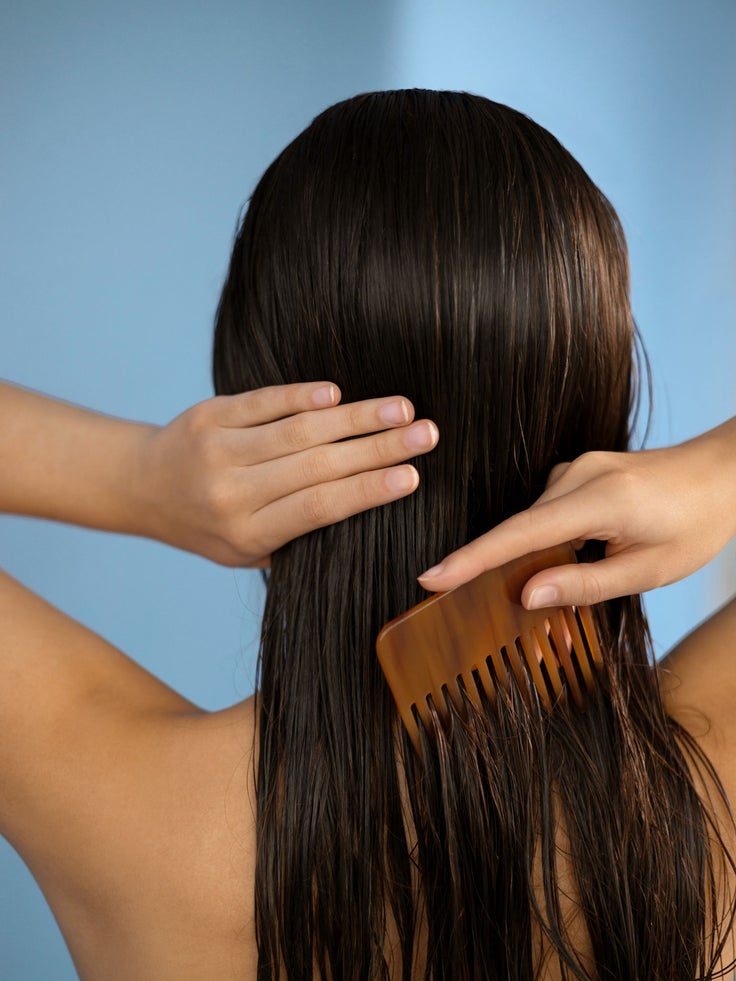 Abgebildet ist eine Frau, die sich die Haare kämmt