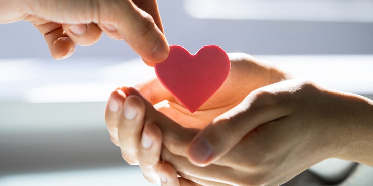 Auf der Grafik ist eine Hand zu sehen die einen Ausschnitt in Herzform in die Hände einer anderen Person legt