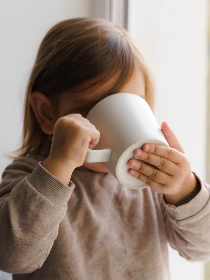 Ein KInd trinkt aus einer Tasse.