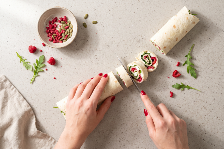 Gefüllter Wrap mit Feta, Rucola und Himbeer-Topping wird in kleine Scheiben für Mini Wraps geschnitten.