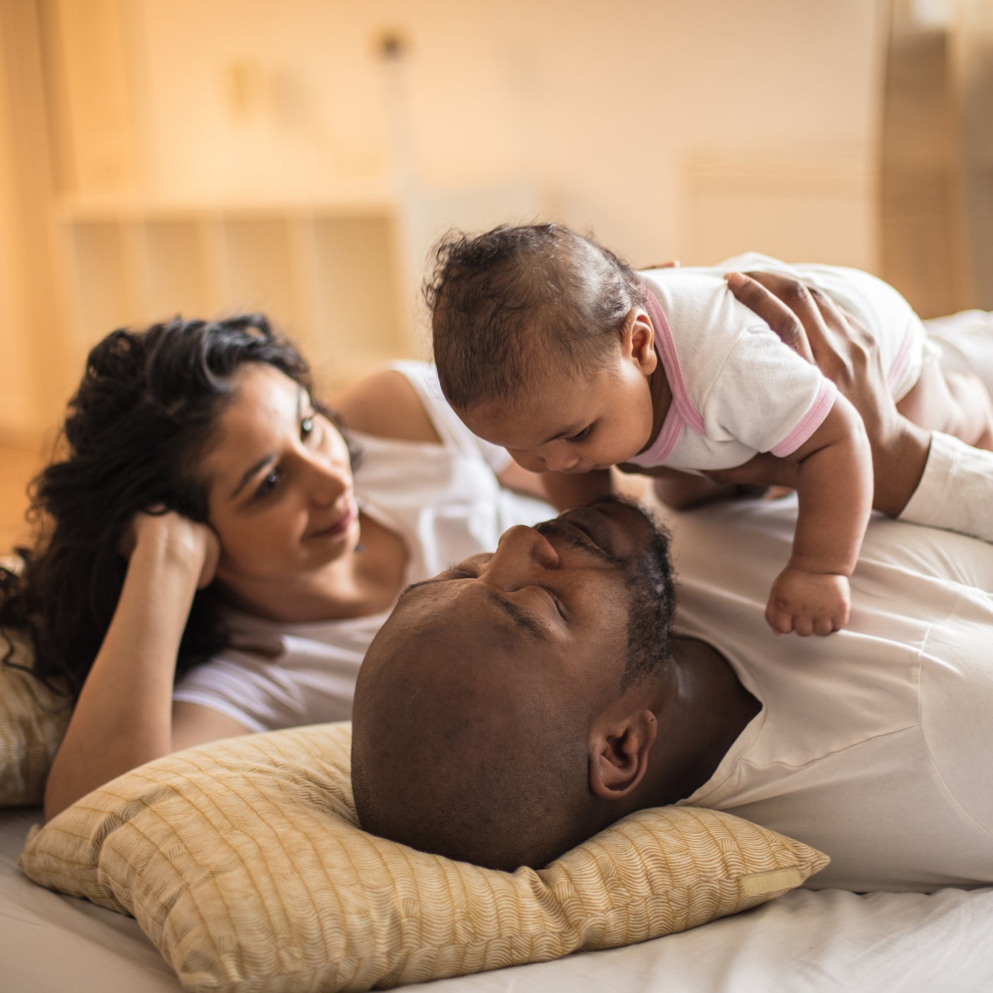 Eltern liegen mit ihrem Baby auf dem Bett und genießen einen ruhigen Familienmoment zu Hause