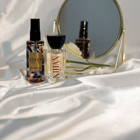 Ein seidenes Tuch mit einem Kosmetikspiegel und den NIHAN Parfum davor