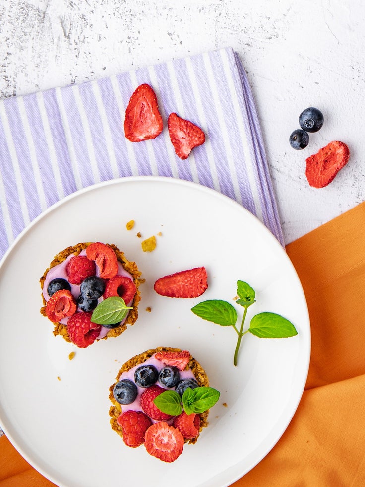 Ein weißer Teller mit 2 Törtchen garniert mit frischen Beeren