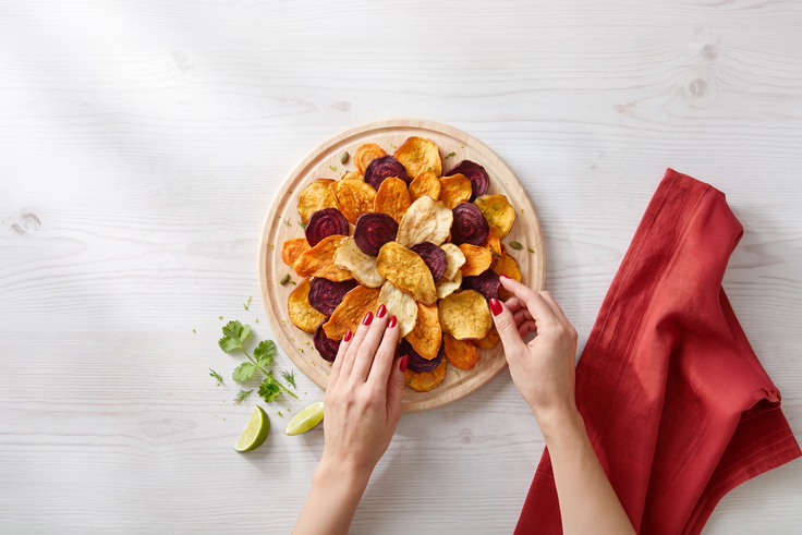 Schritt 1: Hände richten Gemüse Chips auf einem Holzteller an.