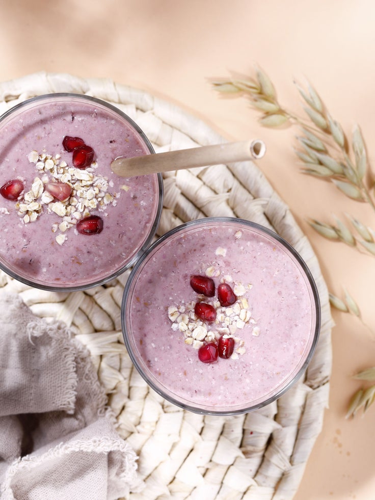 Zwei Gläser mit einem rosa farbenen Müsli Shake auf einem Untersetzer
