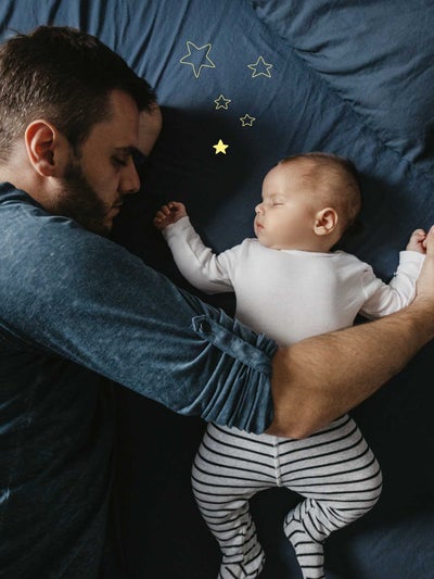 Vater schläft neben seinem schlafenden Baby, das auf blauem Stoff liegt und von goldenen Sternen umgeben ist.