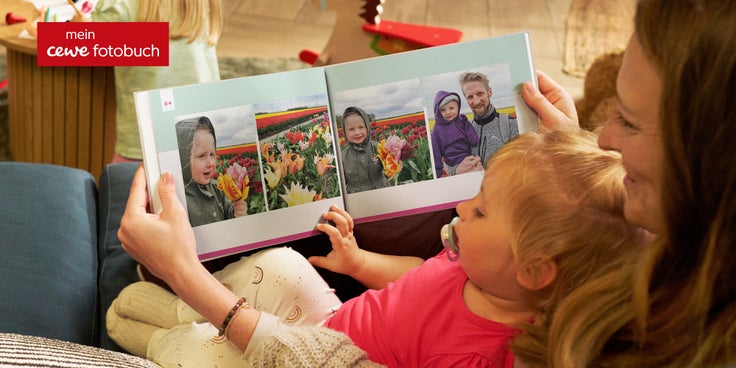 Eine Frau schaut mit einem Kind ein persönliches Fotobuch an.