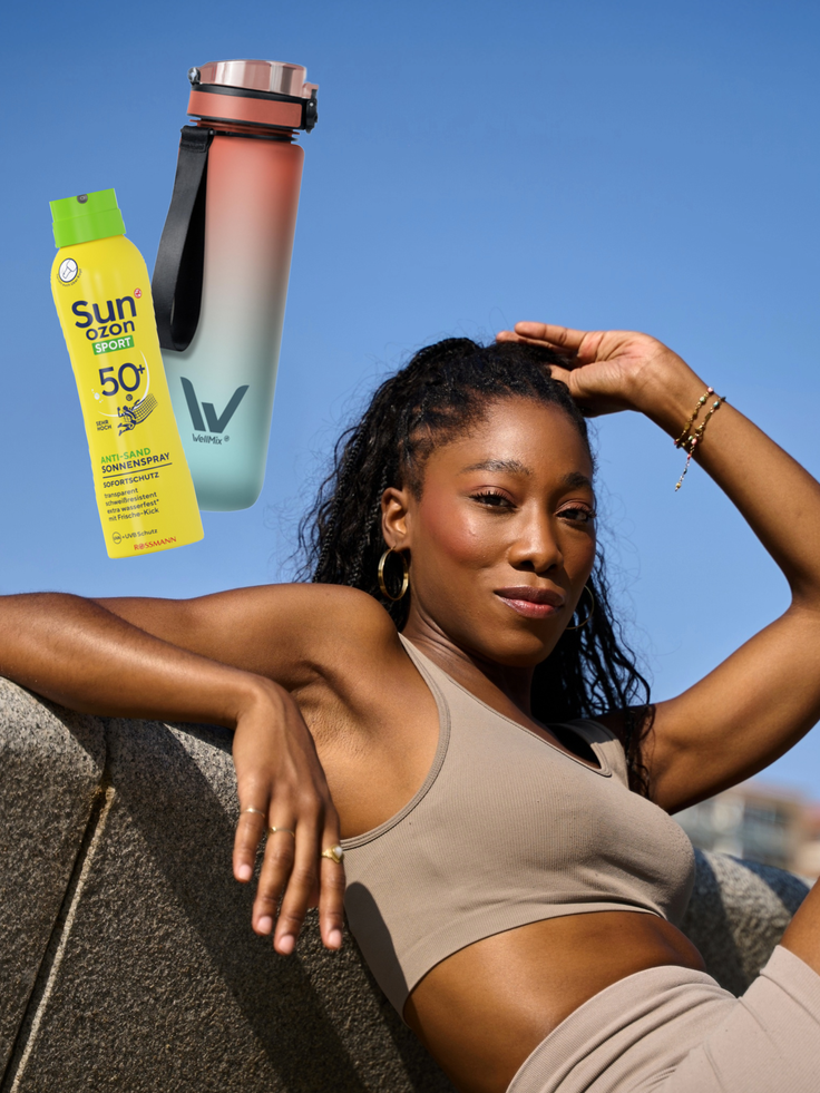 Sunozon Sport Anti-Sand Sonnenspray LSF 50+ und VelmiX Trinkflasche neben einer Frau in sportlicher Kleidung vor blauem Himmel