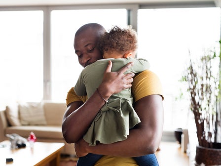 Vater hält sein Kind liebevoll im Arm und tröstet es zu Hause