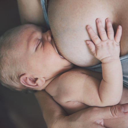 Eine Mutter stillt ihr Kind mit ihrer Brust.